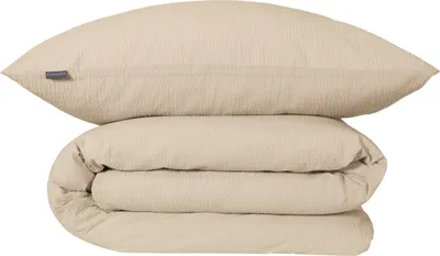 A folded duvet and a pillow are stacked on top of each other against a white background.