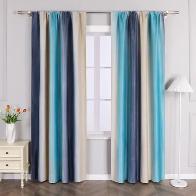 Two curtains with a blue and beige gradient pattern hang in front of a window. A white nightstand with tulips in a vase is to the left, and a white floor lamp is to the right.