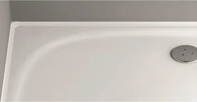 A close-up view of a white shower tray with a silver drain cover.