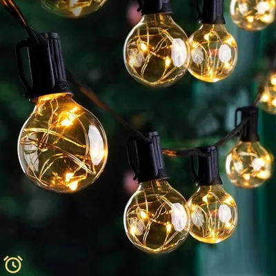 A string of warm white LED lights with clear, globe-shaped bulbs, illuminating a dark, outdoor setting.