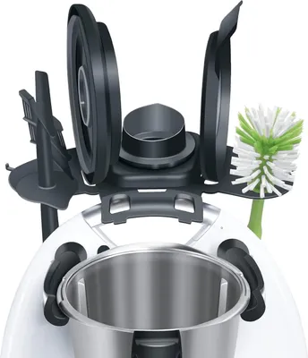 A close-up view of a kitchen appliance accessory holder with various attachments, including a cleaning brush, on a white background.