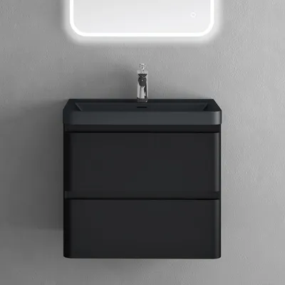 A black vanity with a sink and faucet against a gray wall, under a lighted mirror.