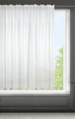 A white sheer curtain hangs in front of a window, with greenery visible outside.