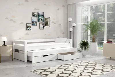 A white daybed with an integrated pull-out bed and drawers, set in a bedroom with decorative wallpaper and a large window.