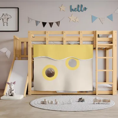 A child's loft bed with a slide and tent-like curtains, decorated with wall art and a rug with toys.