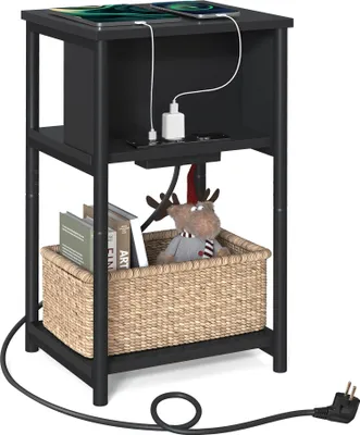 A black side table with a basket and books on the lower shelf, and a tablet and charging cables on the top shelf.