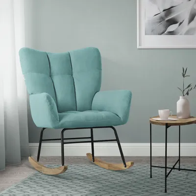 A teal rocking chair with wooden rockers is shown in a room with a light gray wall and a patterned rug.