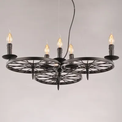 A black chandelier with a wagon wheel design and six candle-shaped lights, suspended against a light gray background.