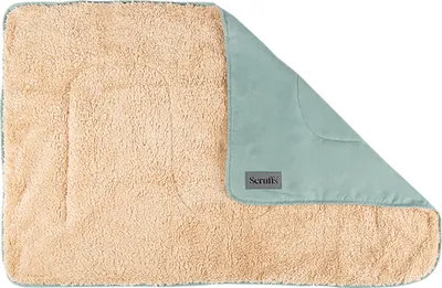 A folded pet blanket with a fluffy tan side and a smooth sage green side, with a brand label visible.