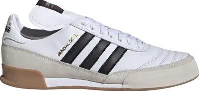 A side view of a white Adidas Mundial Goal indoor soccer shoe with black stripes and tan accents.