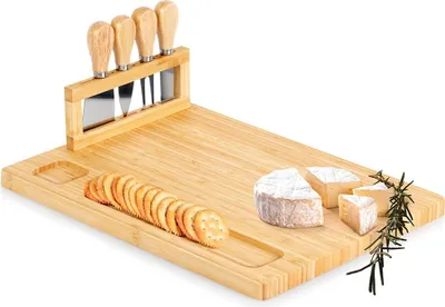 A bamboo cheese board set with cheese knives, crackers, and cheese pieces.