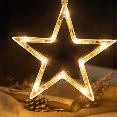 A star-shaped LED light decoration hangs in front of a dark background, with some decorative elements like pinecones and a rolled-up scroll visible in the foreground.