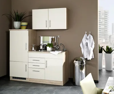 A compact kitchen unit with cabinets, sink, and appliances, set against a brown wall with a window view in the background.