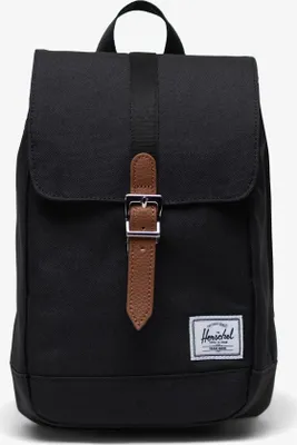 A black Herschel backpack with a brown leather buckle and strap is shown against a white background.