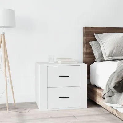 A white nightstand next to a bed with a wooden headboard.