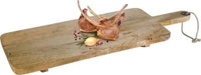 A wooden cutting board with a handle, decorated with two pieces of cooked meat, a sprig of rosemary, a clove of garlic, and peppercorns.
