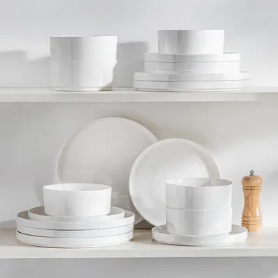 A collection of white ceramic dishes stacked neatly on white shelves.