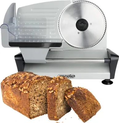 A food slicer with a loaf of bread and two slices in front of it.