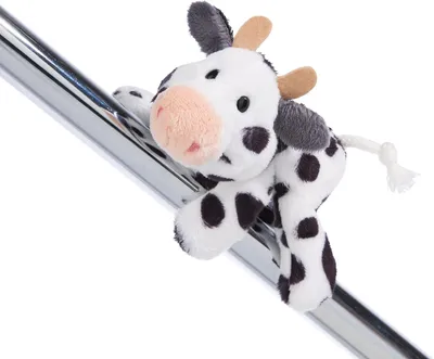 A plush toy cow is draped over a metallic bar.