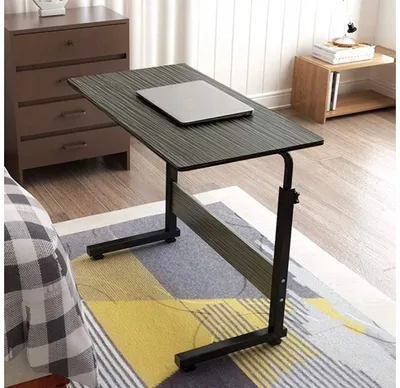 A laptop table is placed next to a bed, with a laptop on top. The room also features a dresser and a small side table.