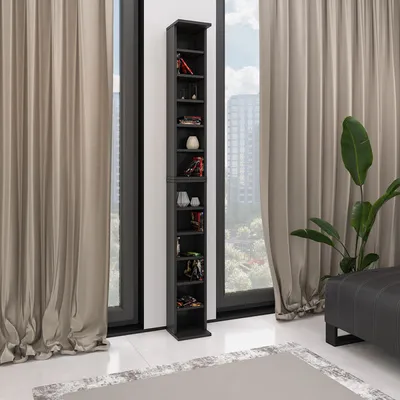 A tall, narrow black shelving unit filled with various small decorative items, positioned in a room with large windows and light-colored curtains.