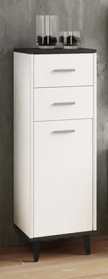 A white cabinet with black top and legs, standing on a wooden floor against a concrete wall.