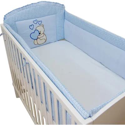 A baby crib with blue and white checkered bedding and a pillow featuring a teddy bear holding a heart.