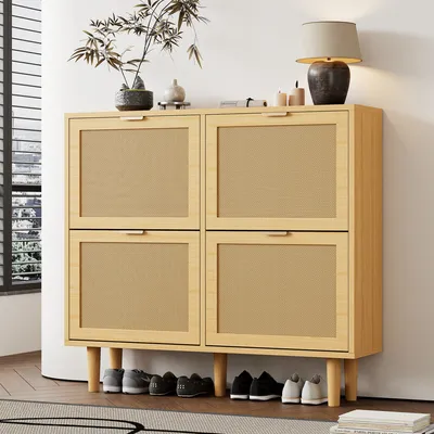 A light oak shoe cabinet with four flip-down drawers, placed in a room with a window and a lamp on top.