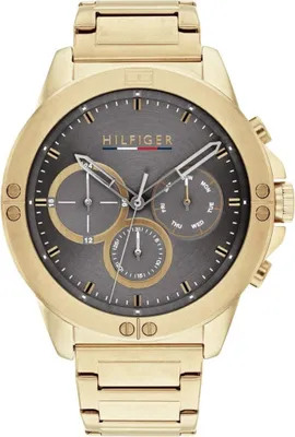 A close-up studio shot of a gold Tommy Hilfiger watch with a gray dial.