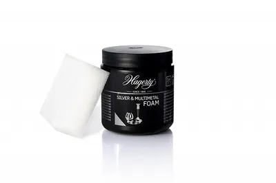 A black jar of Hagerty Silver & Multimetal Foam cleaner with a white sponge next to it, presented on a white background.