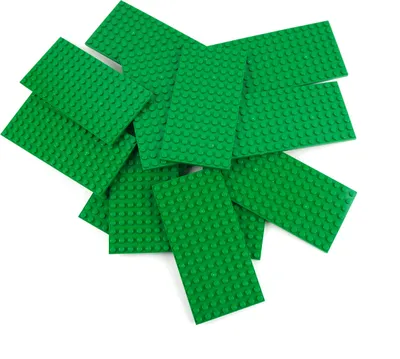 A pile of green LEGO baseplates on a white background.