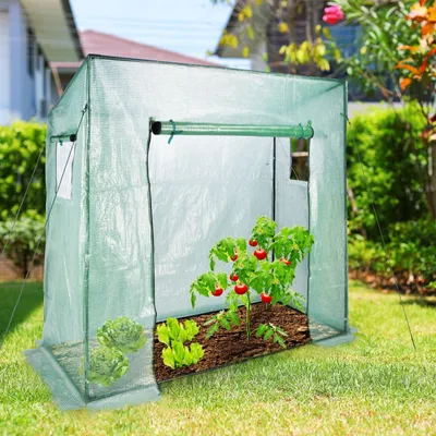 A small greenhouse with plants inside, set up in a garden.