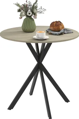 A round dining table with a vase of flowers, a cup of coffee, and a loaf of bread on it.