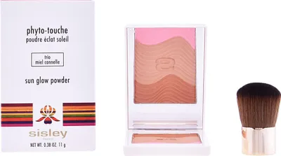 A boxed makeup product, an open compact with makeup, and a makeup brush are displayed against a white background.