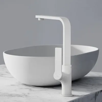 A white matte faucet is shown in front of a white basin, both resting on a marble countertop.