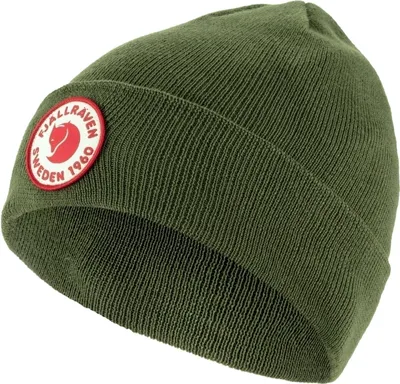 A close-up studio shot of a green knitted beanie with a circular red and white logo patch.