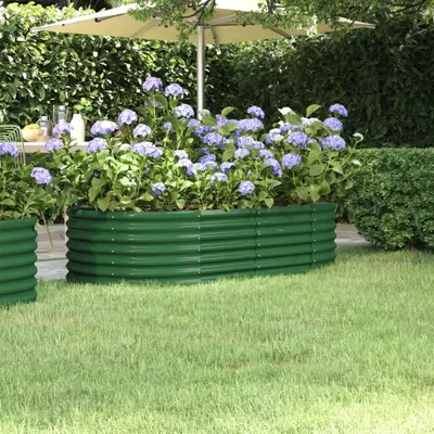 A green raised garden bed filled with purple hydrangeas, set in a garden with a lawn and a hedge.