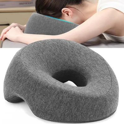 A person is resting their head on a gray pillow designed for napping or office use.