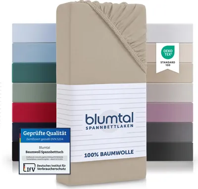 A stack of folded fitted sheets in various colors, with a beige one prominently displayed in the foreground.