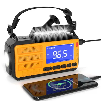 A yellow and black emergency radio with a flashlight and a screen displaying '96.5 FM', with a smartphone charging from it.