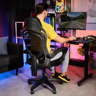 A man is playing a video game in a room with colorful lighting.