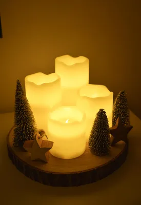 A decorative arrangement of LED candles and miniature Christmas trees on a wooden base.