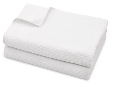 Two white waffle pique sauna towels are neatly folded and stacked on a white background.