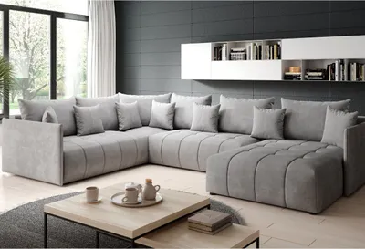 A modern living room with a large sectional sofa, coffee table, and shelves on the wall.
