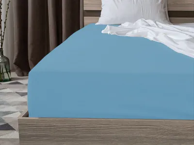 A close-up view of a bed with light blue fitted sheets and a white pillow.