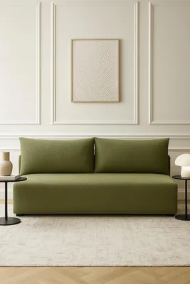 A modern living room with a green sofa and a framed artwork on the wall.