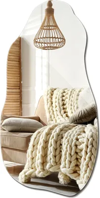 A mirror reflecting a cozy living room scene with a chair and a chunky knit blanket.