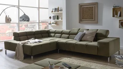 A modern living room with a large sectional sofa, a floor lamp, and shelves with decorative items.