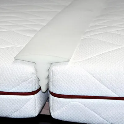 A close-up view of a white mattress topper bridge placed between two mattresses.