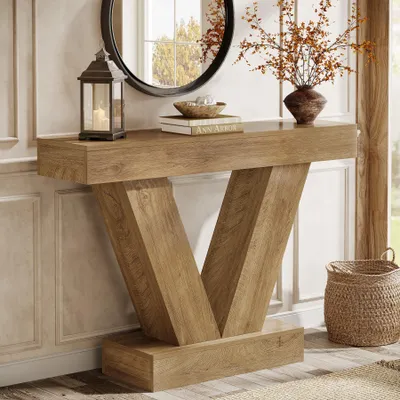 A console table with a V-shaped base is shown in a room setting, decorated with a lantern, books, and a vase with branches.